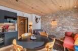 Discover the charm of this cozy living space, featuring a rustic stone wall and a warm wooden ceiling.