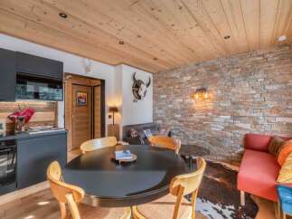 Discover the charm of this cozy living space, featuring a rustic stone wall and a warm wooden ceiling.