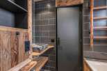 This stunning bathroom boasts a rustic design with wooden accents and dark gray tiles, creating a cozy and inviting atmosphere.