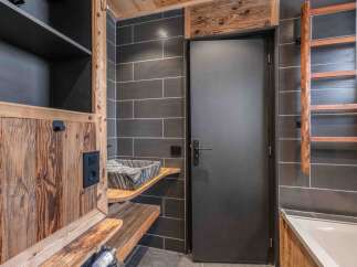This stunning bathroom boasts a rustic design with wooden accents and dark gray tiles, creating a cozy and inviting atmosphere.