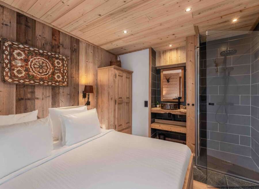 Experience rustic luxury in this stunning bedroom featuring a cozy wooden interior and a modern bathroom.