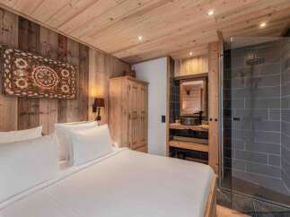 Experience rustic luxury in this stunning bedroom featuring a cozy wooden interior and a modern bathroom.