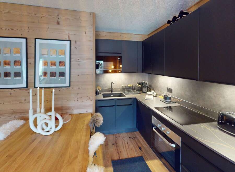 This modern kitchen features sleek black cabinetry, a stylish countertop, and a built-in oven.