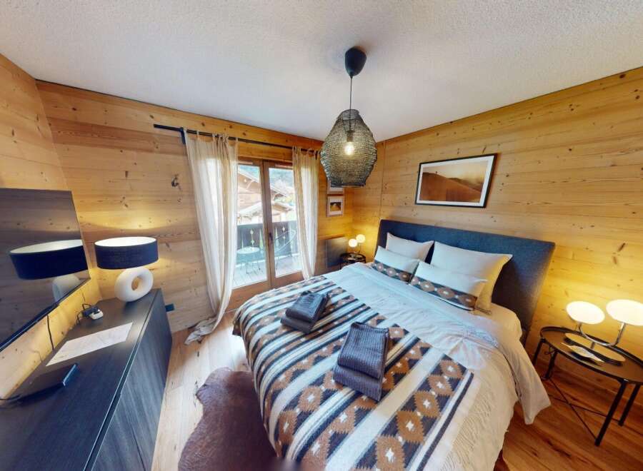 Experience the warmth of this cozy bedroom featuring stunning wood paneling and a comfortable bed.