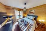 Experience the warmth of this cozy bedroom featuring stunning wood paneling and a comfortable bed.