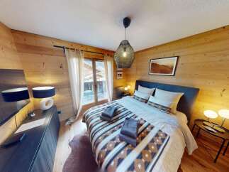 Experience the warmth of this cozy bedroom featuring stunning wood paneling and a comfortable bed.