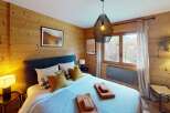 Discover the charm of this cozy bedroom, featuring warm wooden walls and a stylish pendant light.
