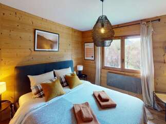 Discover the charm of this cozy bedroom, featuring warm wooden walls and a stylish pendant light.