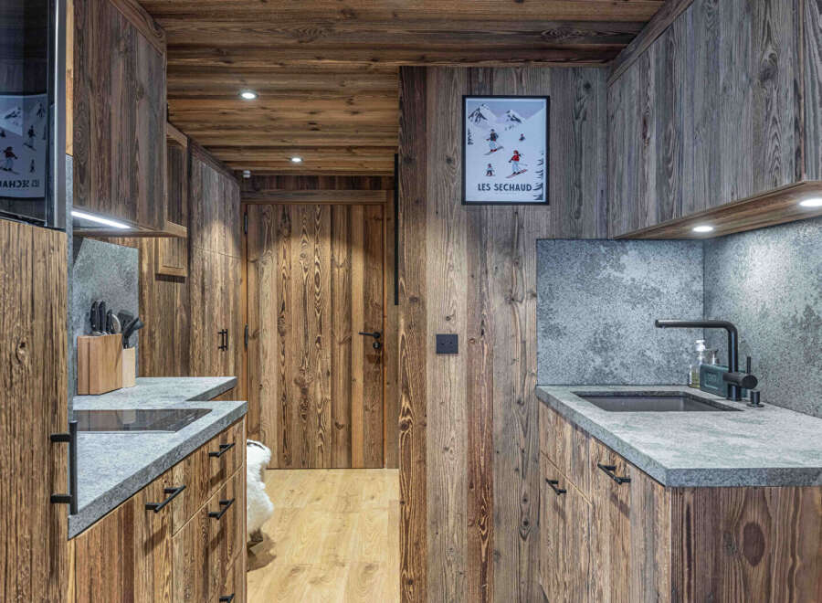 This stunning kitchen showcases rustic charm with its warm wooden paneling and sleek countertops.