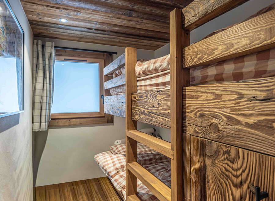 This charming bedroom features rustic bunk beds crafted from beautiful wood, creating a cozy and inviting space.