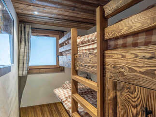 This charming bedroom features rustic bunk beds crafted from beautiful wood, creating a cozy and inviting space.
