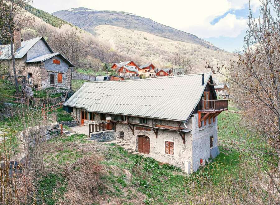 Discover the charm of this stunning mountain property, featuring a rustic stone facade and a modern metal roof.