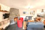 Experience the warmth and charm of this stunning property, featuring a cozy living room with a stone fireplace and a mounted TV.