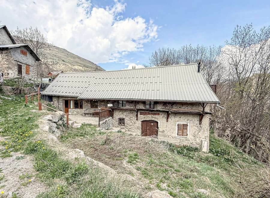 Discover a charming stone house nestled in a picturesque mountain setting.