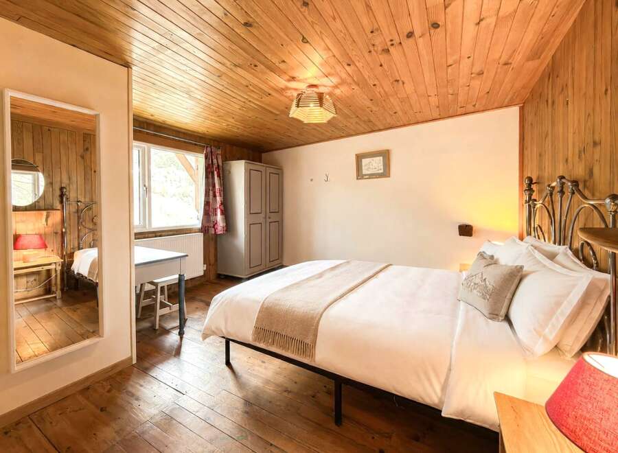 This cozy bedroom features a warm wooden ceiling and flooring, creating a rustic and inviting atmosphere.