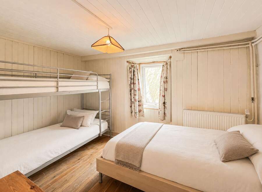 This charming bedroom features a cozy bunk bed and a comfortable double bed, perfect for families or groups.
