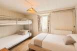 This charming bedroom features a cozy bunk bed and a comfortable double bed, perfect for families or groups.
