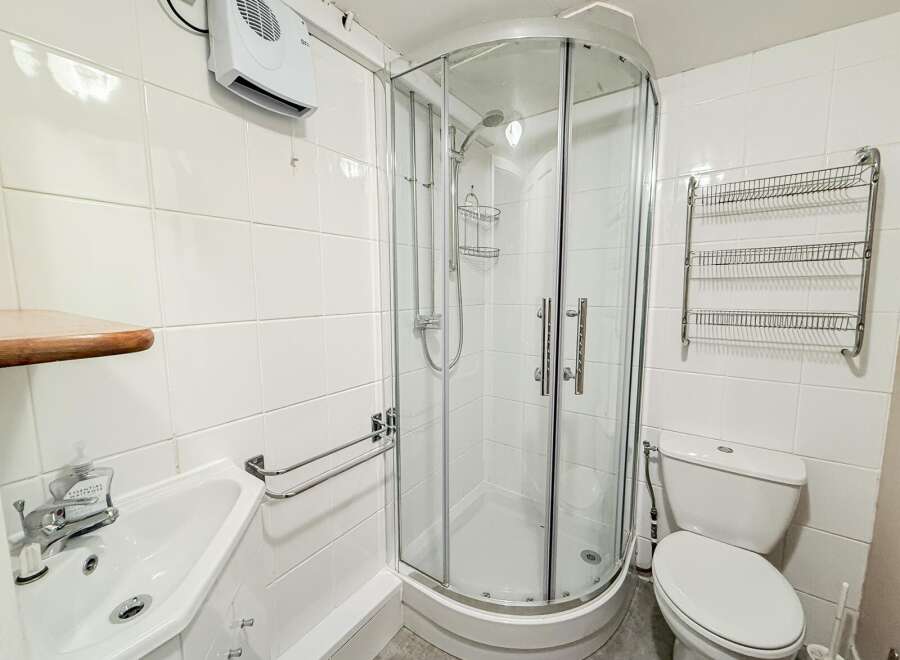 This well-maintained bathroom features a modern shower enclosure, perfect for a refreshing start to your day.