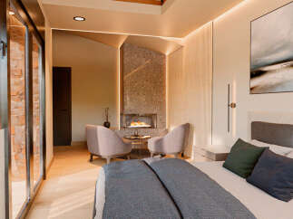 Experience luxury living in this stunning bedroom featuring a cozy fireplace and elegant seating area.