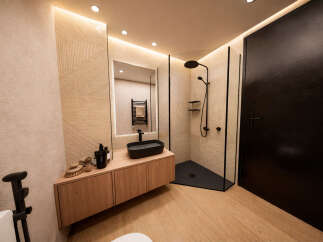 Step into a modern bathroom oasis! This stunning space features a sleek black sink atop a wooden vanity, complemented by a stylish shower enclosure.