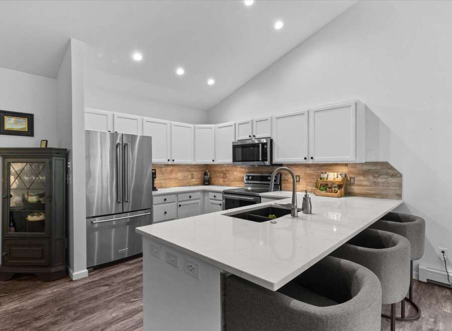 This modern kitchen boasts sleek white cabinetry and a stunning quartz countertop with a waterfall edge, perfect for entertaining.