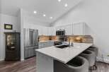 This modern kitchen boasts sleek white cabinetry and a stunning quartz countertop with a waterfall edge, perfect for entertaining.