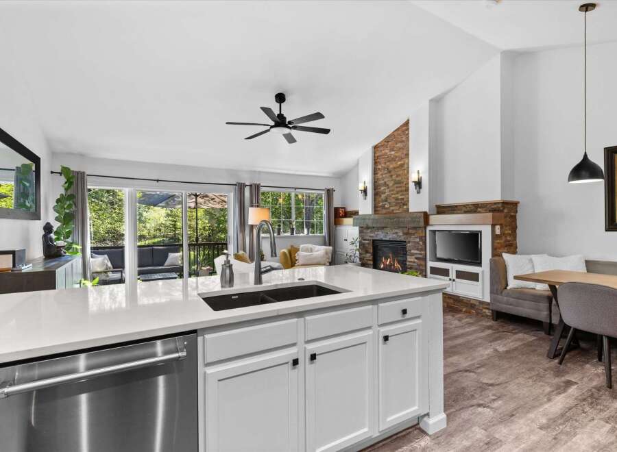 Experience modern living in this stunning open-concept home, featuring a sleek kitchen island with a double sink and stainless steel dishwasher.