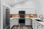 This modern kitchen features sleek white cabinetry, a stainless steel refrigerator, and a matching range with a built-in microwave.
