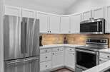 This modern kitchen features sleek stainless steel appliances, including a French door refrigerator and a matching range with a smooth cooktop.