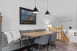 This dining area features a comfortable banquette with plush white pillows, complemented by a modern wooden table and two upholstered chairs.