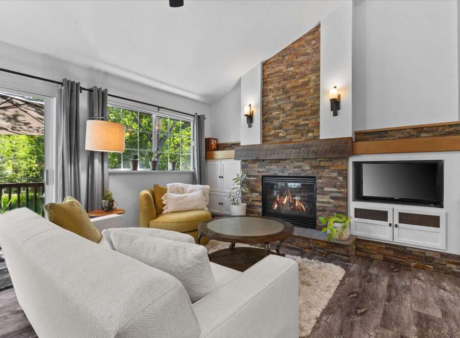 Cozy living room featuring a stunning floor-to-ceiling stacked stone fireplace with a rustic wood mantel.