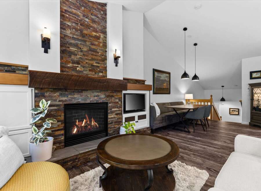 Cozy living room featuring a stunning floor-to-ceiling stone fireplace with a rustic wood mantle.