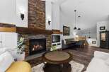 Cozy living room featuring a stunning floor-to-ceiling stone fireplace with a rustic wood mantle.