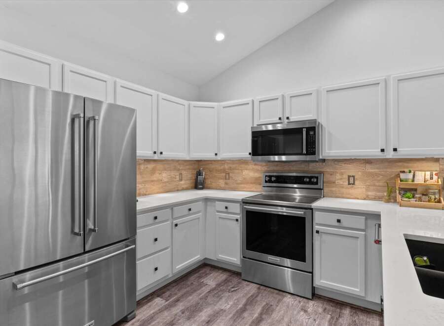 This modern kitchen boasts sleek stainless steel appliances, including a French door refrigerator and a built-in microwave.