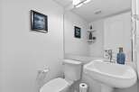 This charming powder room features a pristine white pedestal sink with a modern chrome faucet, complemented by a decorative blue soap dispenser.