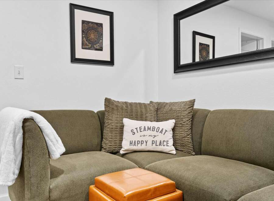 Cozy up in this inviting living space featuring a comfortable sectional sofa adorned with decorative pillows and a plush throw blanket.