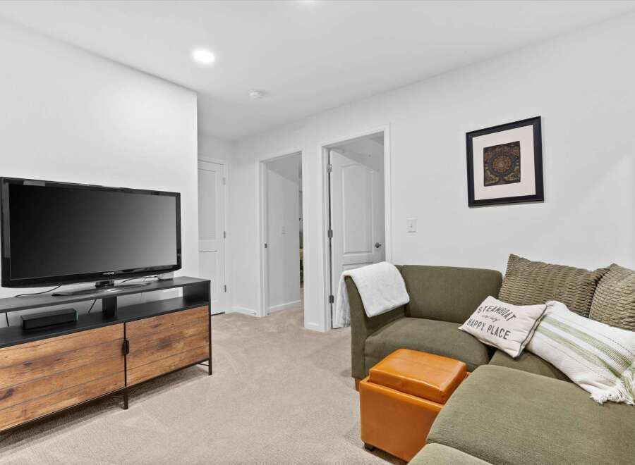 This inviting living space features a large flat-screen TV mounted above a stylish wooden media console, perfect for entertainment.