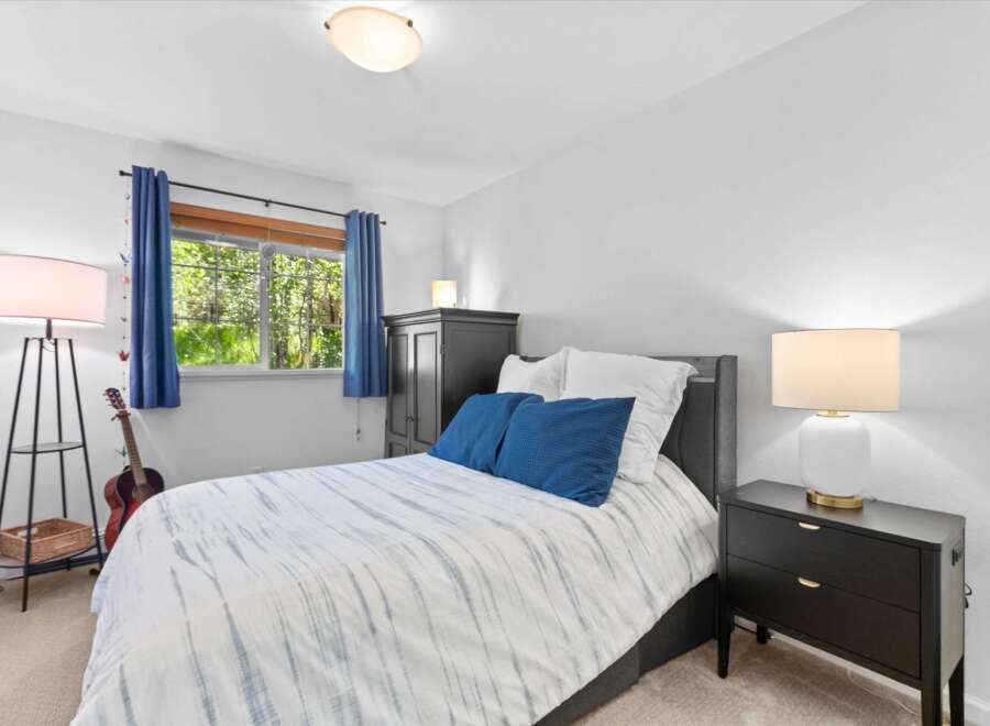 This inviting bedroom features a comfortable queen-size bed with a stylish blue and white striped comforter, complemented by two plush blue throw pillows.