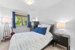 This inviting bedroom features a comfortable queen-size bed with a stylish blue and white striped comforter, complemented by two plush blue throw pillows.