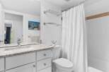 This bright and clean bathroom features a spacious vanity with a granite countertop and ample storage.