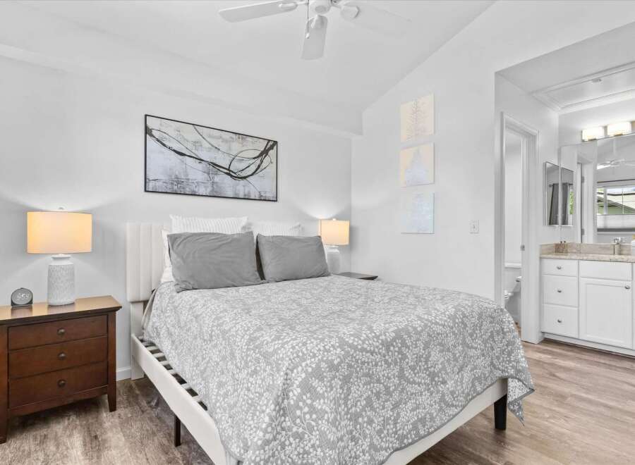 Discover comfort and style in this inviting bedroom, featuring a plush queen-size bed adorned with a charming floral-patterned comforter and coordinating gray pillows.