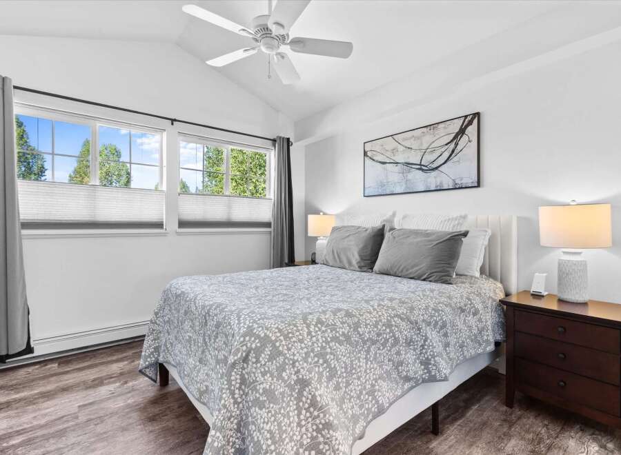 Experience comfort and style in this beautifully appointed bedroom, featuring a plush queen-size bed adorned with a charming floral-patterned quilt and coordinating grey pillows.