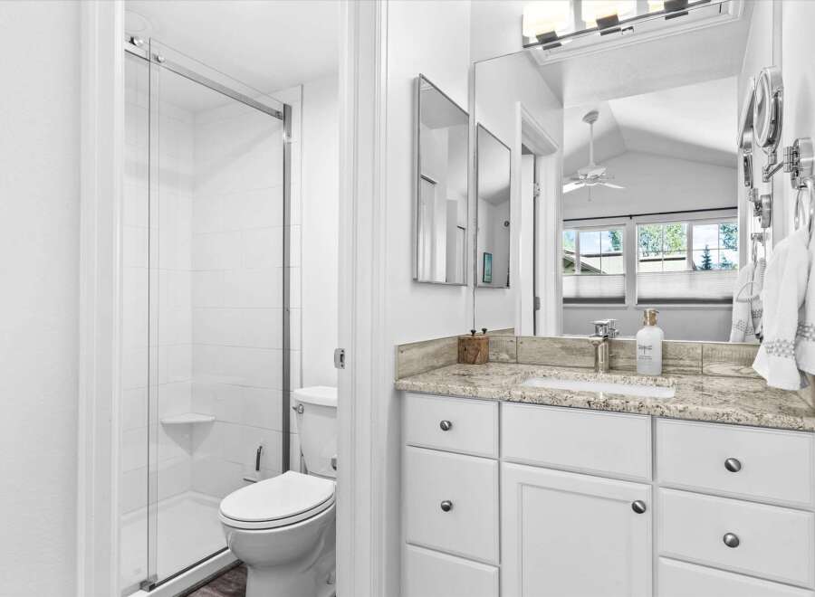 This bright and airy bathroom features a spacious walk-in shower with white tiled walls and a convenient corner shelf.