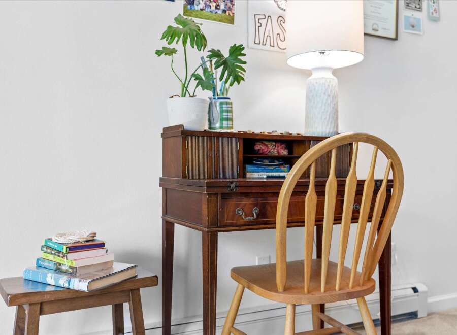Discover a charming workspace featuring a vintage wooden secretary desk adorned with a potted plant and decorative items.