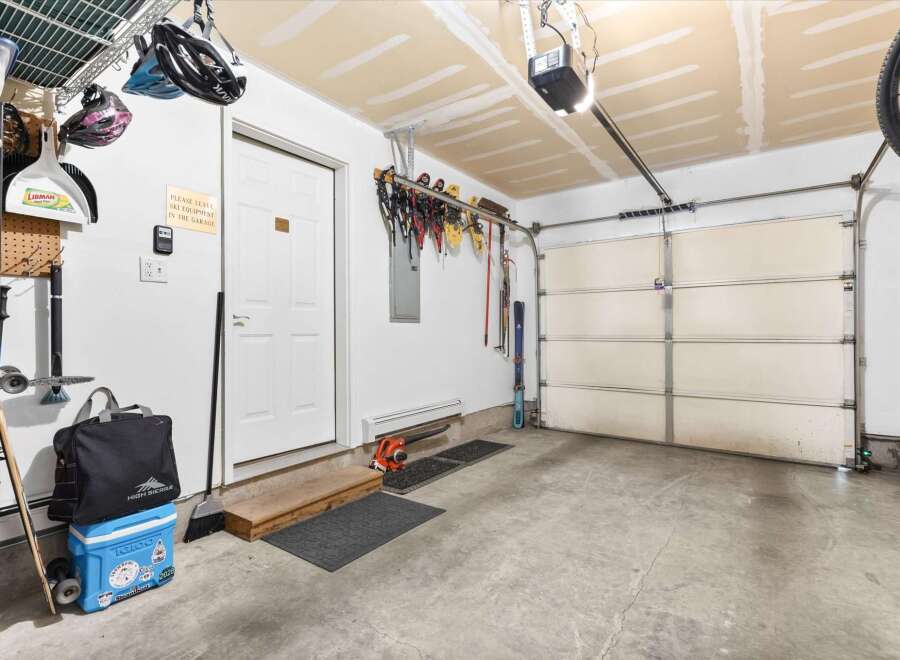 This spacious garage offers ample storage solutions, including overhead shelving and wall-mounted racks perfect for organizing sports equipment like skis and helmets.