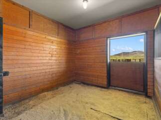 Step into this inviting horse stall, featuring warm wood paneling and a clean, spacious interior.