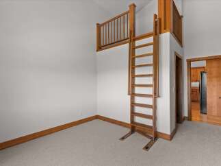 Discover a unique property featuring a charming loft area accessible by a wooden ladder, perfect for a cozy retreat or extra storage.