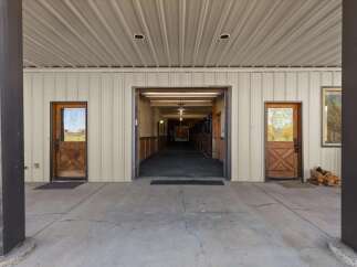 Discover the charm of this equestrian property, featuring a spacious covered walkway leading to a well-lit stable.
