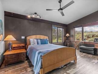 Step into this inviting bedroom, featuring a cozy bed and a rustic nightstand.