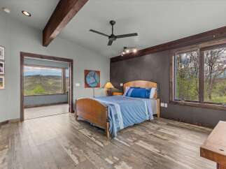 This stunning bedroom boasts a serene ambiance with its rustic wooden accents and breathtaking views.